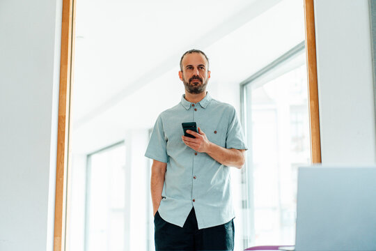 Self-employed developer using smartphone in modern office