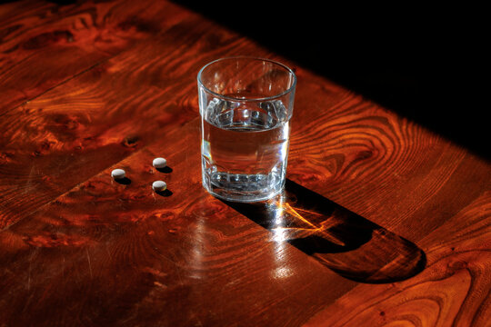 Glass of water and analgesic pills on table for pain relief concept
