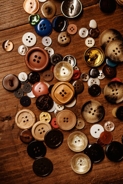 Assorted colorful buttons scattered on wooden surface