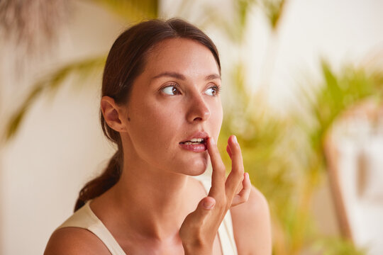 Lip care woman touching lips with finger eyes closed, natural lip balm beauty routine in tropical outdoor setting with palm bokehCopy title