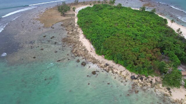 Aerial drone footage of Oar paradise small island from above, in Sumur city, in Pandeglang regency, Java island, Indonesia, nearby Ujung Kulon national park, blue sea and white sand, reef and rocks
