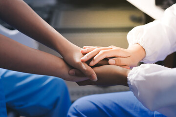 Obraz premium Gentle Hand Holding by Healthcare Worker in Teal Scrubs Offering Comfort and Support in Bright Modern Medical Office with Light Gray Background