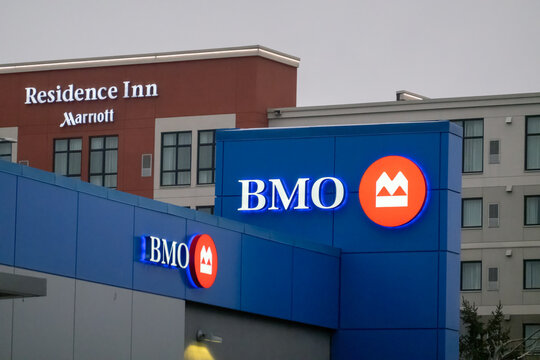 Calgary, Alberta, Canada. April 2, 2026. Illuminated BMO bank signage on a blue building exterior with a Residence Inn Marriott hotel in the background.