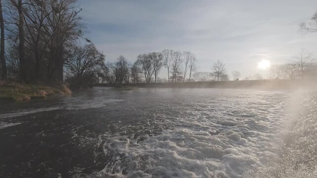 Morning view of the Opavice River with flowing water over a small weir. Peaceful natural landscape with fresh atmosphere, perfect for nature, travel, and environmental background concepts.