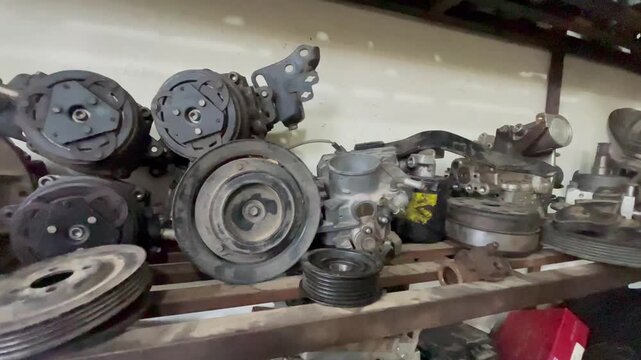 Automotive AC Compressors and Engine Pulleys at Workshop &ndash; Car Repair Mechanical Parts Close-Up, Shot in a real workshop environment with natural lighting, highlighting industrial textures and detail
