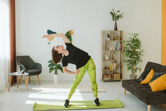 Young woman stretching side bend at home for fitness