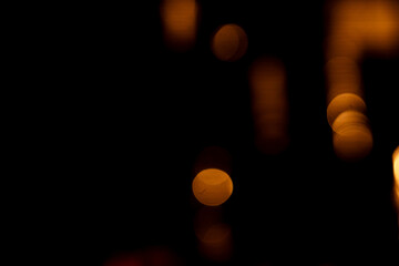 Fototapeta premium Blurred background defocused abstract golden bokeh circles against a dark background, creating a mysterious and dreamy atmosphere.