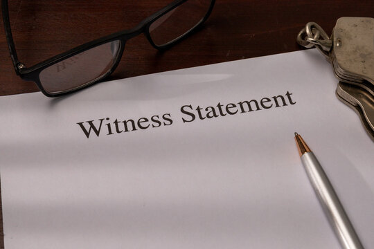 Close-up of a Witness Statement Document with Glasses, Pen, and Handcuffs on a Desk