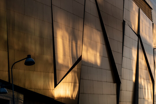 Minimal architectural wall facade with warm light and deep shadow showing urban geometry and textured surfaces for abstract background