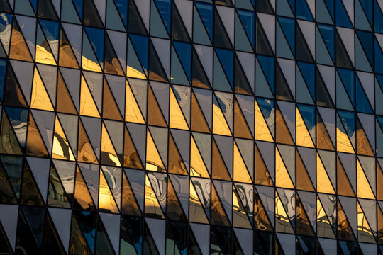 Warm reflections across a modern glass facade with geometric pattern and clean symmetry creating an abstract architectural surface