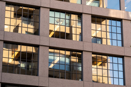 Warm toned urban office building facade showing concrete grid windows and modern architecture detail with subtle reflection