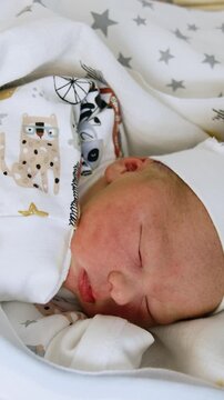 Tiny Caucasian newborn in cap and shirt. Baby sleeps in blankets and opens his mouth. Vertical video