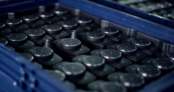 Large group of black circular control dials with icons organized in a blue plastic industrial crate