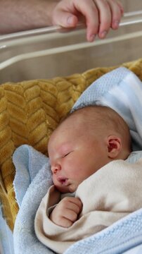 Lovely Caucasian baby sleeping in a crib. Unrecognized man sits near the cradle of his newborn child. Top view. Vertical video
