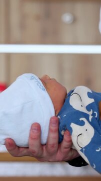 Adorable newborn in blue romper and white cap. Father is holding a baby in front of him. Vertical video