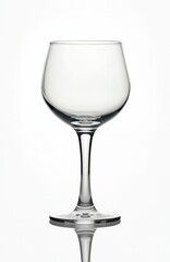 Fototapeta premium Clear wine glass with rounded bowl and slender stem rests on reflective surface against bright white backdrop. Suitable for beverage ads, bar menus, and party invitations.