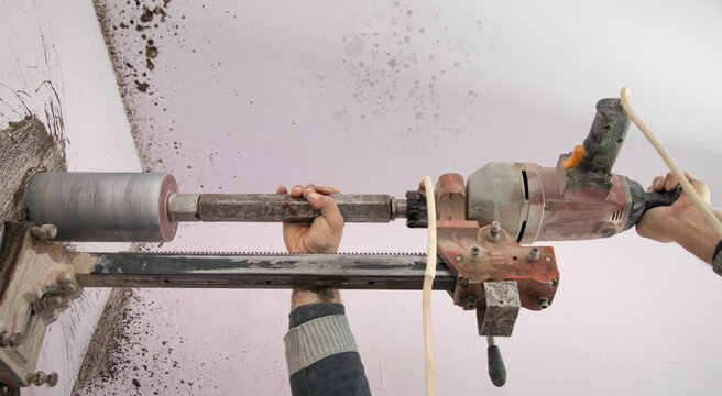 Caucasian worker using concrete core drilling machine.