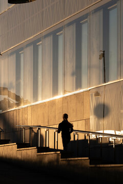 Stockholm Sweden modern glass architecture with stairs as pedestrian silhouette moves through sunlight and shadow creating calm urban rhythm