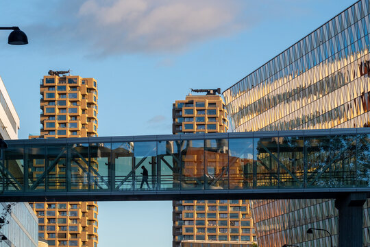 Modern Stockholm Sweden office architecture features glass skybridge walkway linking building forms with reflection across facade in daylight