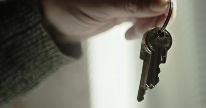 Arm dangling a set of doorkeys on a keyring in a bright room. Perfect for housing market news, rental agency promos, and moving day content.