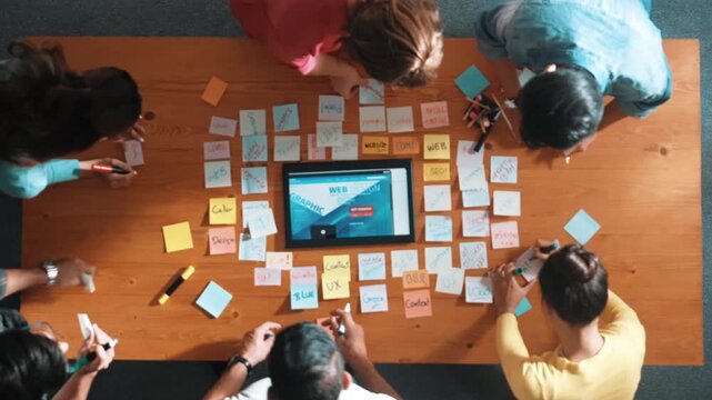 Time lapse of programmer brainstorming and planning about web design while looking at tablet wireframe prototype. Aerial view of skilled developer team talking about digital application. Symposium.