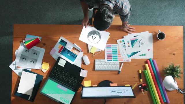 Top view of smart businessman hand choosing color palettes while designing logo graphic. Aerial view of professional interior designer design and select color theme by using color palettes. Symposium.