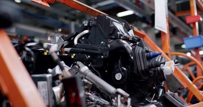 Close up of complex black plastic automotive component with tubes on a factory assembly line
