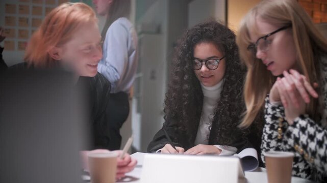 Professional women discussing project strategy around a tablet during a collaborative office session. Female colleagues, coworkers or team members sharing opinions, reviewing information, planning