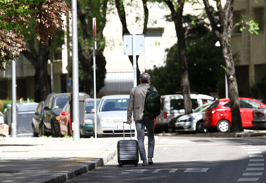 Viajero caminando por la carretera con maleta por asfalto y carril bus con equipaje