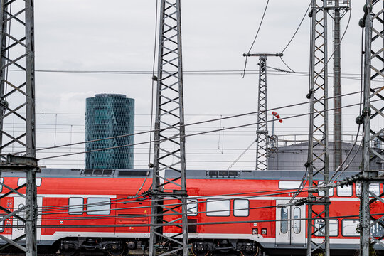 Overhead wires above railway in Frankfurt Germany frame a red train as transport infrastructure supports daily commute corridor today