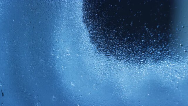 Ice crystals melting across a surface with blue tones and black background featuring frozen water, crystal formation, cold environment with winter