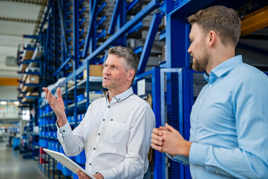 Business meeting in factory production hall with employee discussion