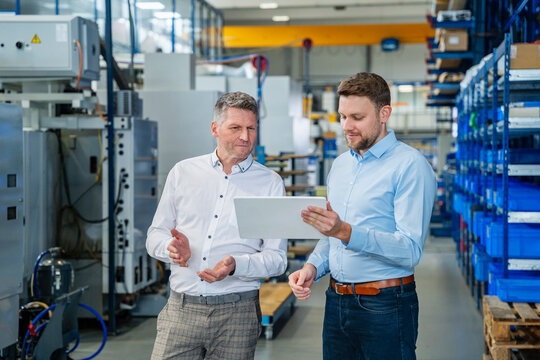 Business meeting between employees with tablet in production hall