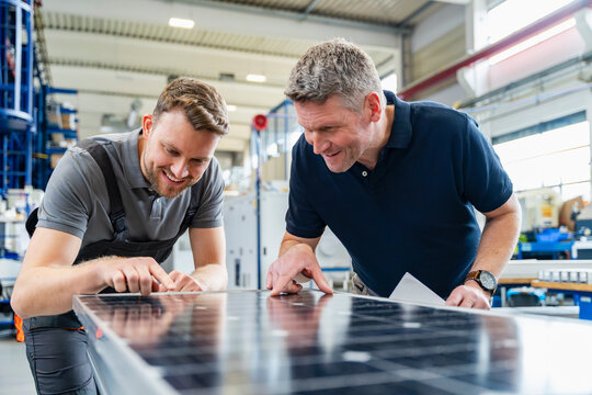 Employees reviewing solar panel in production hall meeting