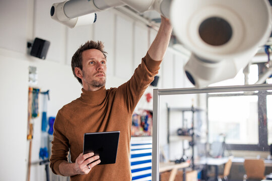 Engineer holding tablet PC and adjusting extraction arm at workshop