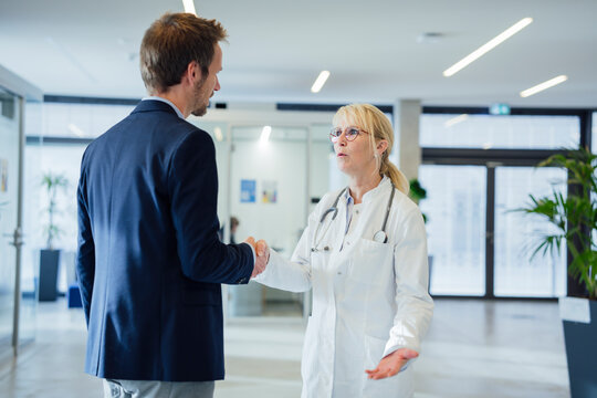 Doctor shaking hands with man in hospital