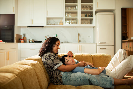 Two women cuddling on sofa in cozy home kitchen