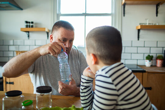 Father teaching son about recycling at the kitchen table