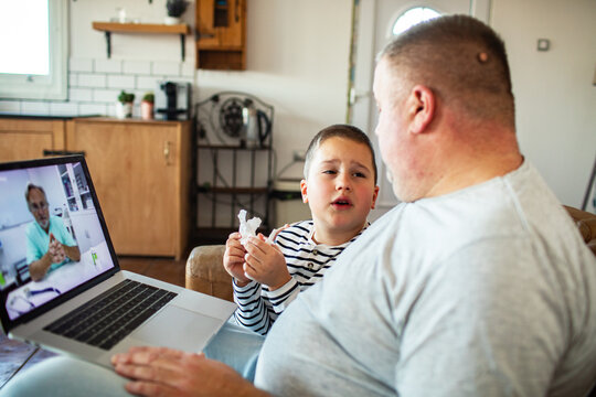 Father comforts sick son during telehealth video consultation at home