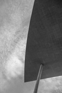 Brutalist concrete roof overhang architecture with pole under cloudy sky showing minimalist geometry and abstract modern structural design