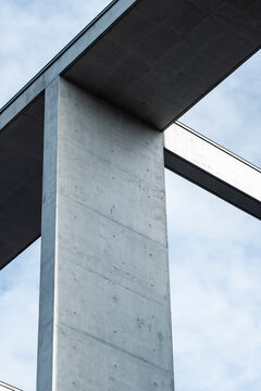 Concrete bridge architecture with modern pillar structure against blue sky creating minimalist brutalist geometry lines and abstract infrastructure