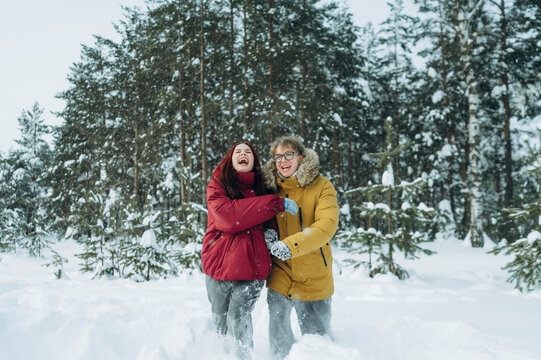 Happy couple in winter forest smiling and embracing in the snow