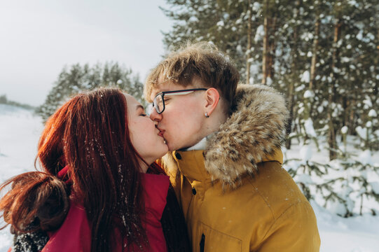 Romantic couple kissing in snowy winter forest outdoors