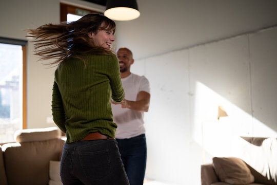 Couple laughing and dancing together in living room at home