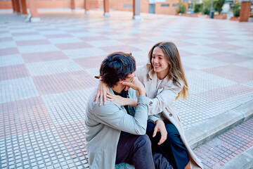 Fototapeta premium Happy young couple embracing and laughing in an urban setting, representing love, connection, and relationship goals