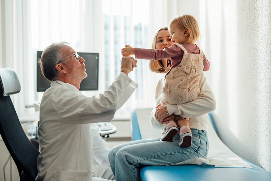 Pediatrician examining child with mother in hospital office