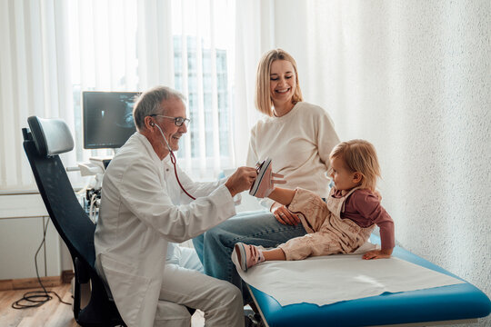 Doctor examining child with mother during check up in hospital