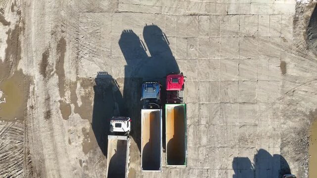 Aerial view of multiple trucks positioned on a construction site, with visible cargo containers and surrounding machinery, showcasing the organized layout and operational workflow of the area