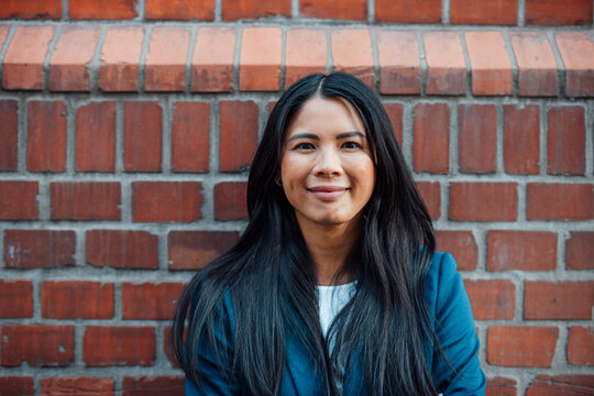 Smiling businesswoman in front of brick wall