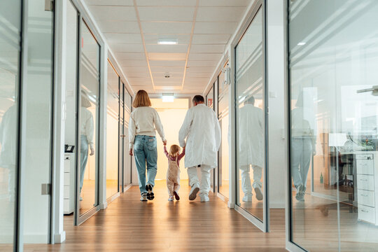 Doctor walking with child and parent in hospital corridor